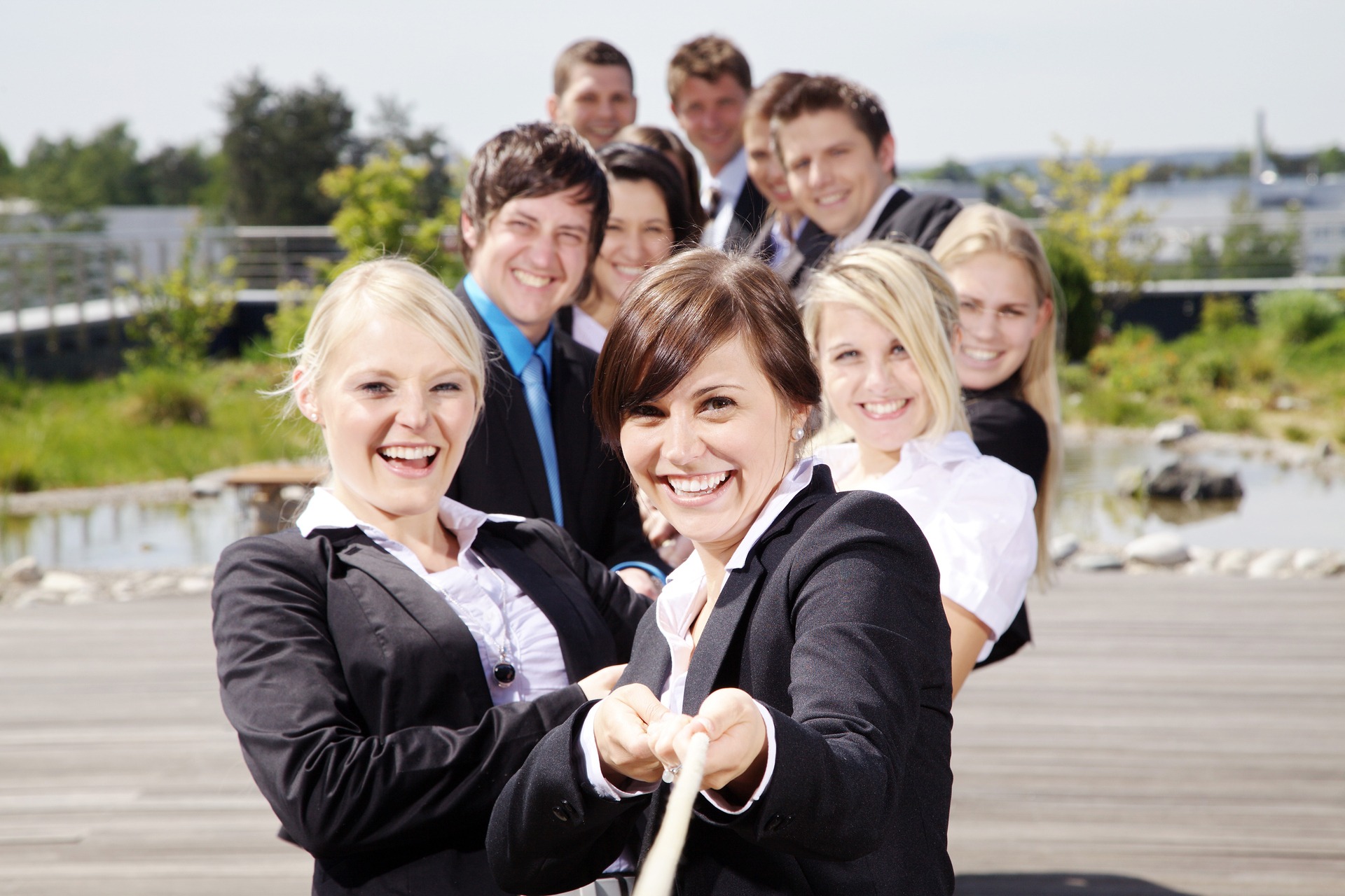 Team zieht an einem Tau und freut sich Team zieht an einem Tau - Teambuilding